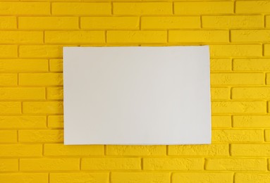 Photo of Blank canvas on yellow brick wall. Space for design