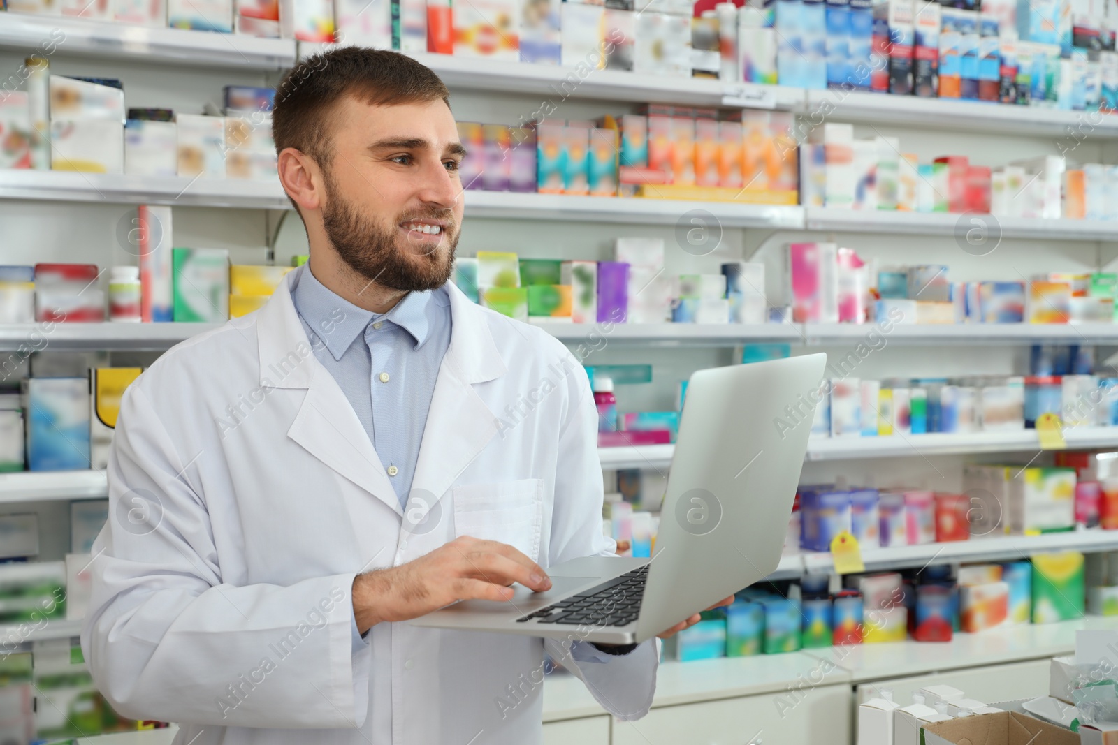 Image of Professional pharmacist with laptop in modern drugstore