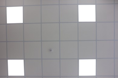 Photo of White ceiling with PVC tiles and lighting indoors, bottom view