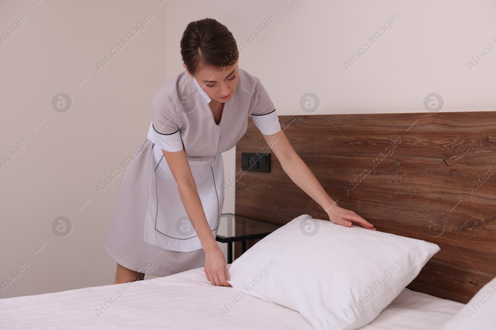 Photo of Beautiful chambermaid making bed in hotel room