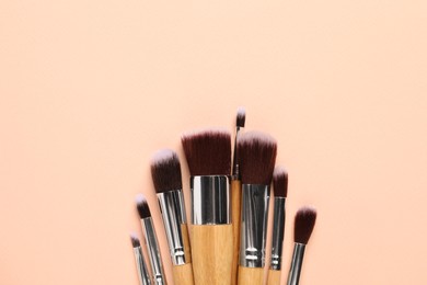 Set of makeup brushes on beige background, flat lay. Space for text