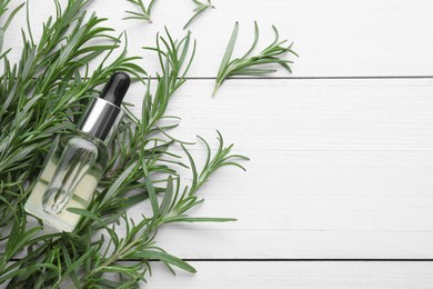 Photo of Fresh green rosemary and bottle of essential oil on white wooden table, flat lay. Space for text