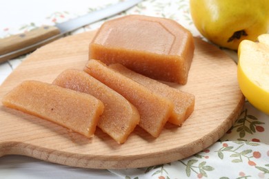Photo of Tasty sweet quince paste, fresh fruits and knife on white wooden table, closeup