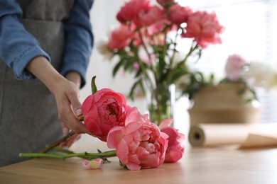 Photo of Florist making beautiful peony bouquet at table, closeup