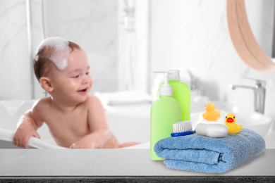 Baby cosmetic products, toys and towel on table in bathroom