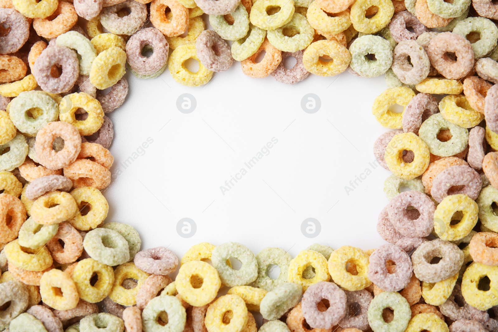 Photo of Frame made of tasty cereal rings on white background, top view. Space for text