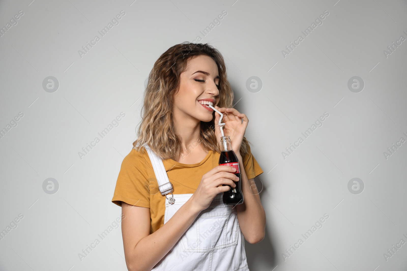 Photo of MYKOLAIV, UKRAINE - NOVEMBER 28, 2018: Young woman with bottle of Coca-Cola on white background