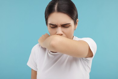 Photo of Woman coughing on light blue background. Cold symptoms