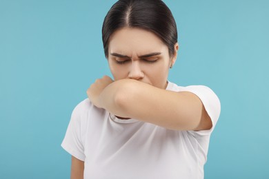 Woman coughing on light blue background. Cold symptoms