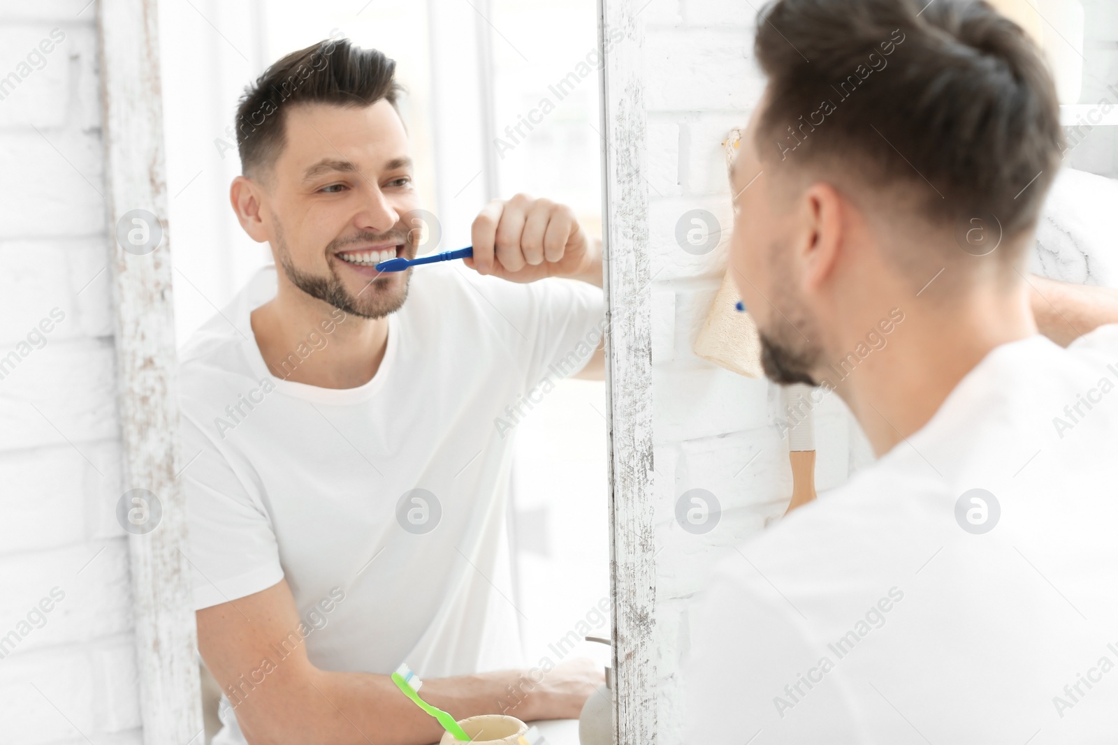 Photo of Young man brushing his teeth in bathroom