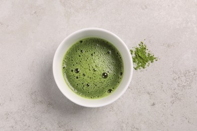 Photo of Cup of matcha tea on light gray textured table, top view
