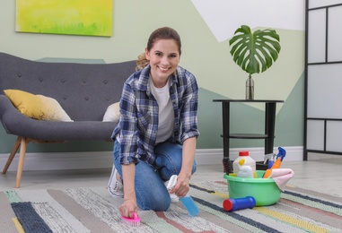 Woman cleaning carpet with brush at home