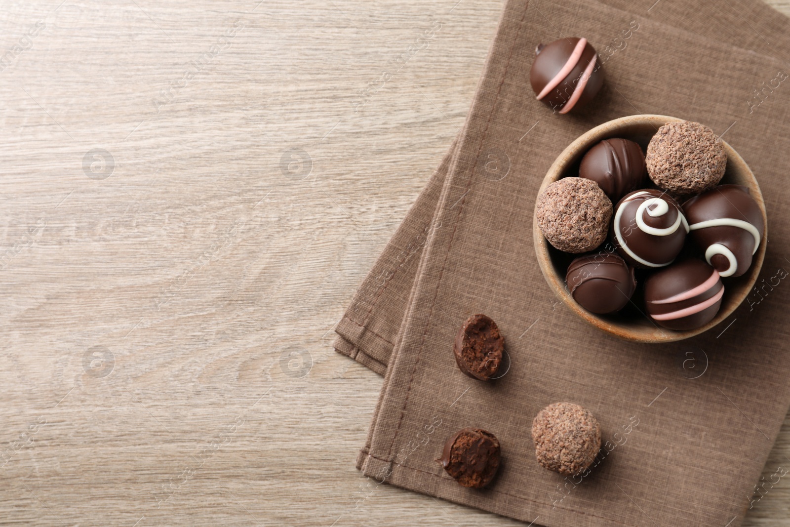 Photo of Many different delicious chocolate truffles on wooden table, top view. Space for text