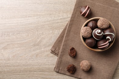 Many different delicious chocolate truffles on wooden table, top view. Space for text