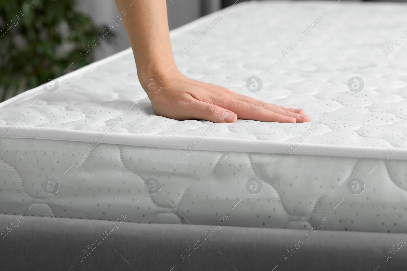 Photo of Man touching soft mattress indoors, closeup view