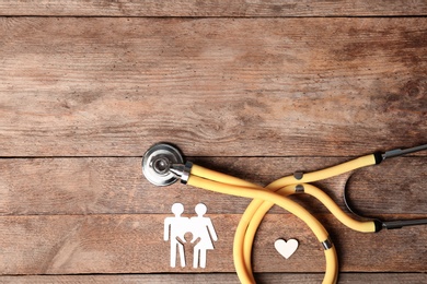 Flat lay composition with heart, stethoscope and paper silhouette of family on wooden background, space for text. Life insurance concept