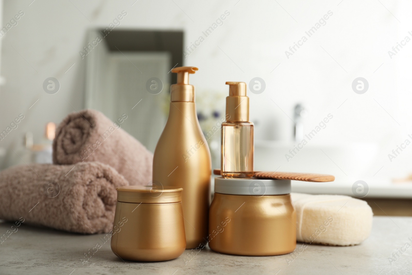 Photo of Different hair care products, towels and comb on table in bathroom