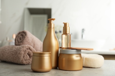 Photo of Different hair care products, towels and comb on table in bathroom