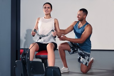 Photo of Happy trainer explaining woman how to do exercise properly in modern gym
