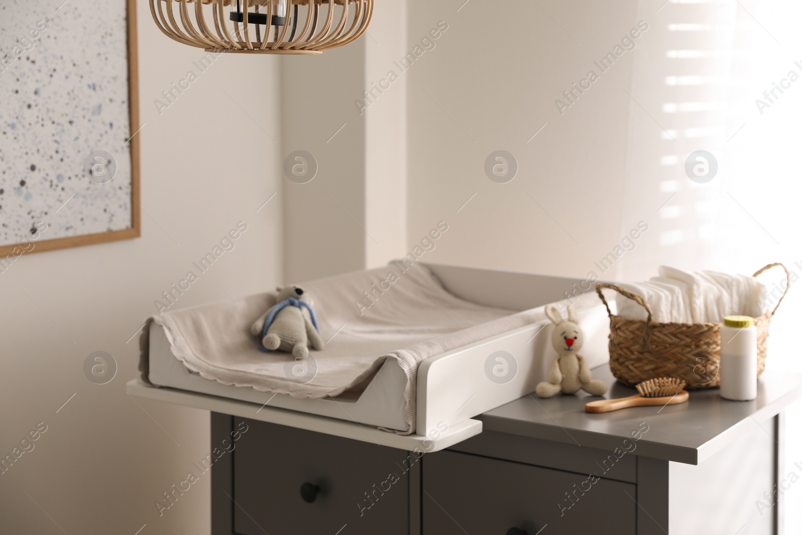 Photo of Chest of drawers with changing pad and tray in nursery. Baby room interior design