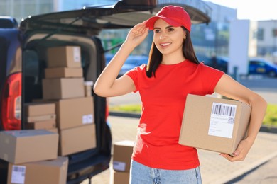 Photo of Courier with parcel near delivery van outdoors, space for text