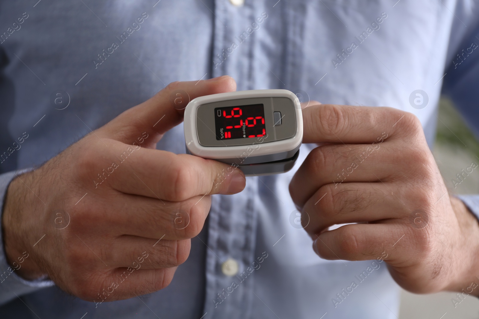 Photo of Man measuring oxygen level with modern fingertip pulse oximeter, closeup