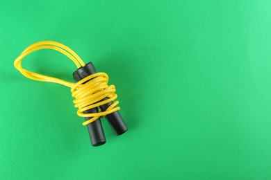 Photo of Skipping rope on green background, top view. Space for text