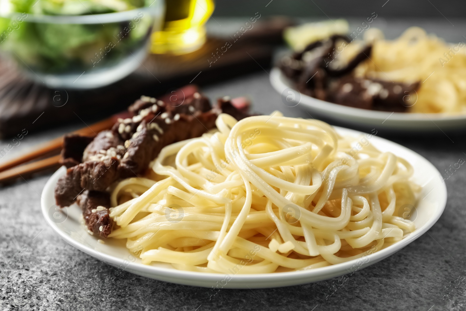 Photo of Tasty cooked rice noodles with meat on grey table