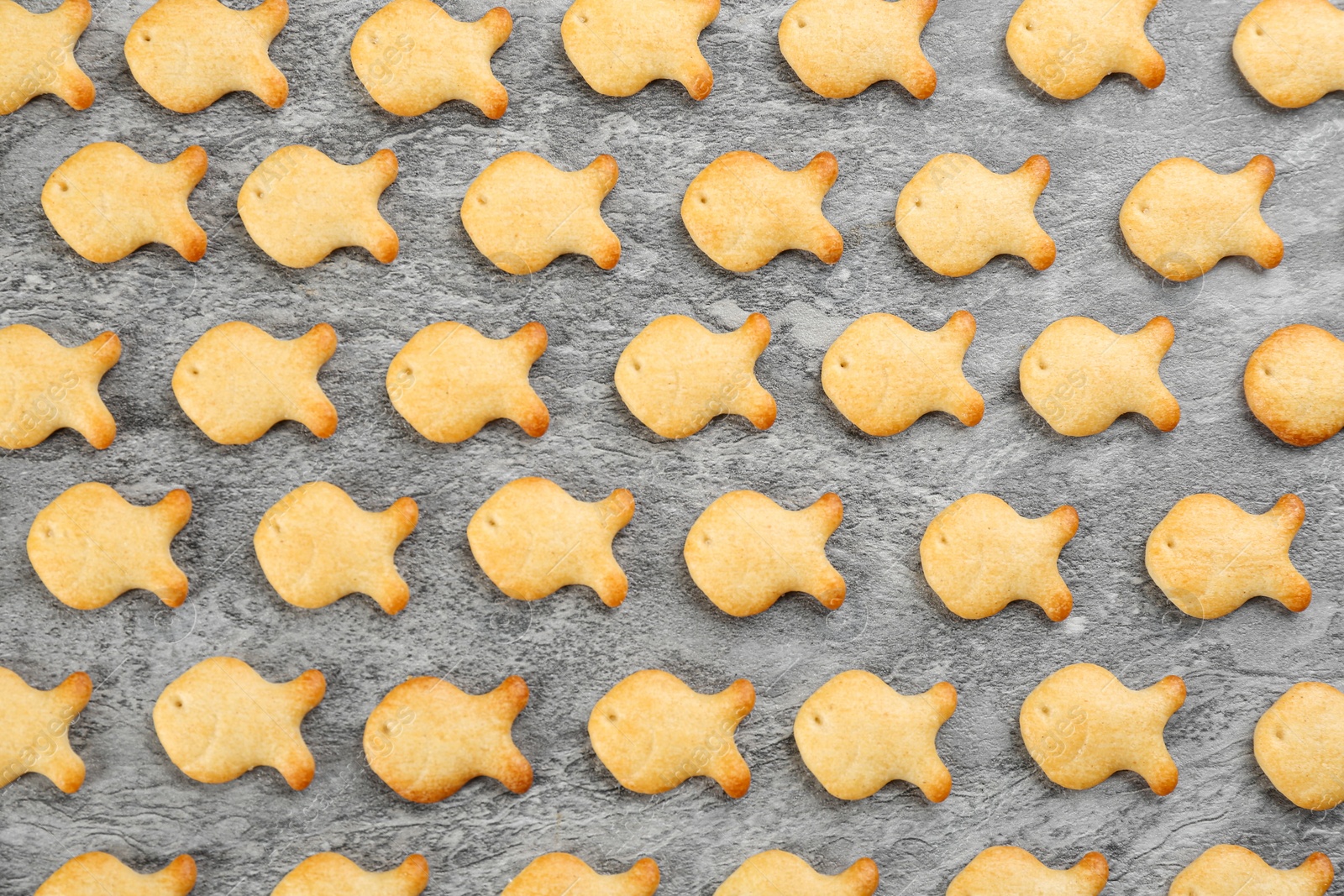 Photo of Delicious goldfish crackers on grey table, flat lay