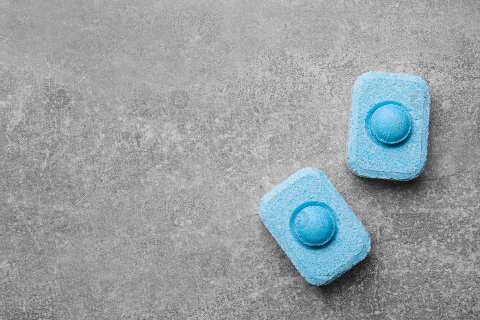 Photo of Water softener tablets on grey table, flat lay. Space for text