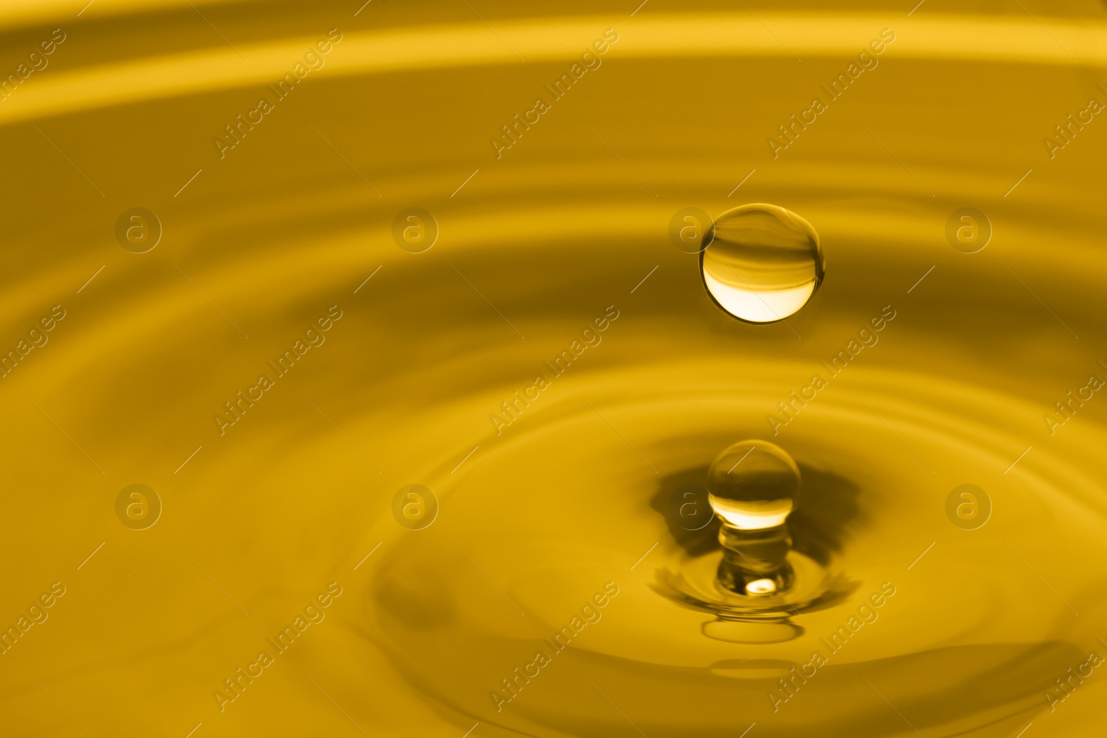 Image of Splash of golden oily liquid with drop as background, closeup. Space for text