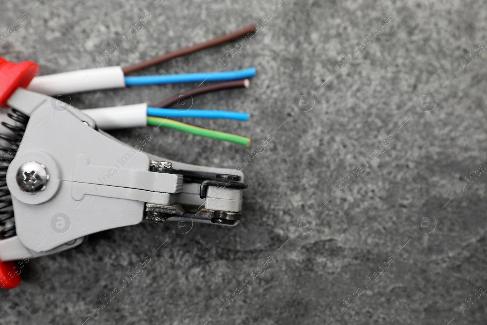 Photo of Professional cutters and cable with stripped wire on grey textured table, flat lay. Space for text