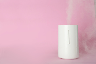 Photo of Modern air humidifier on pink background. Space for text