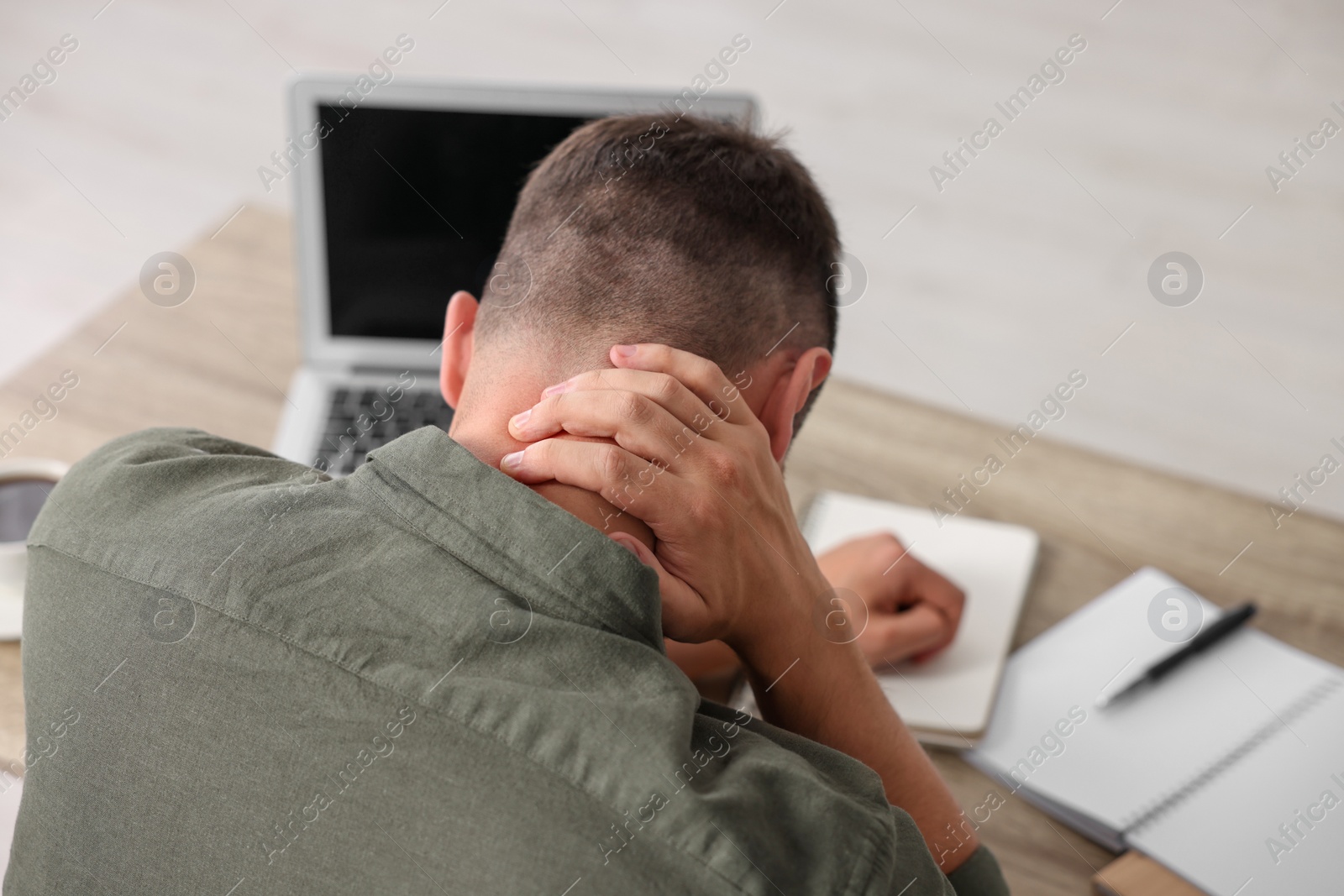 Photo of Man suffering from neck pain in office, back view