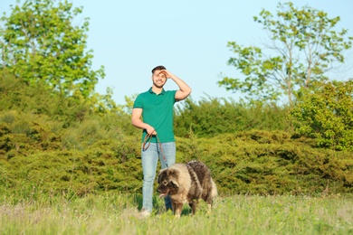 Photo of Young man walking his Caucasian Shepherd dog in park