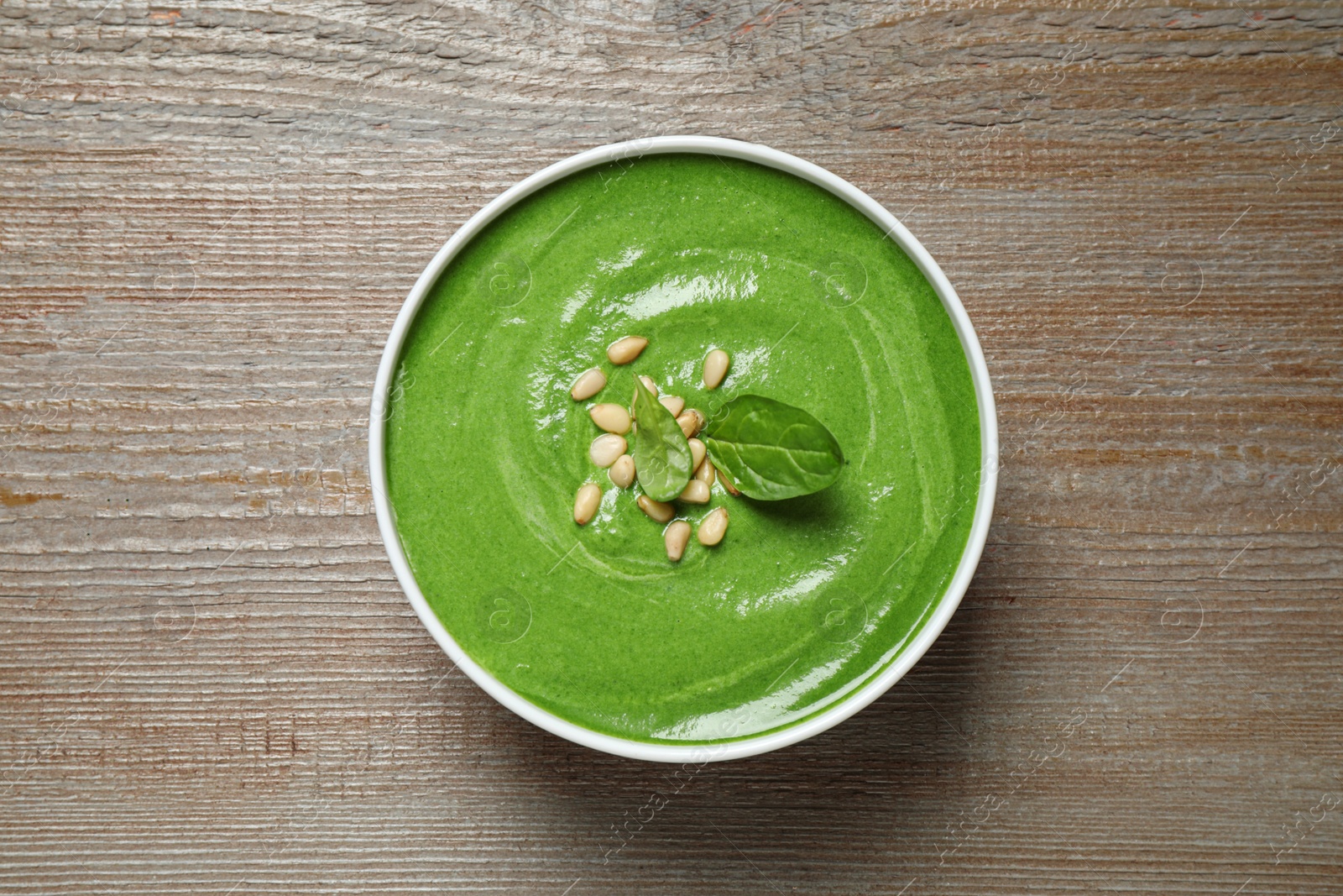 Photo of Bowl of healthy green soup with fresh spinach on wooden table, top view