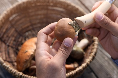 Photo of Man cleaning mushroom with brush at table, closeup