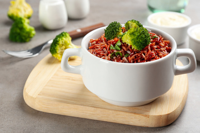 Tasty brown rice with broccoli on light grey table