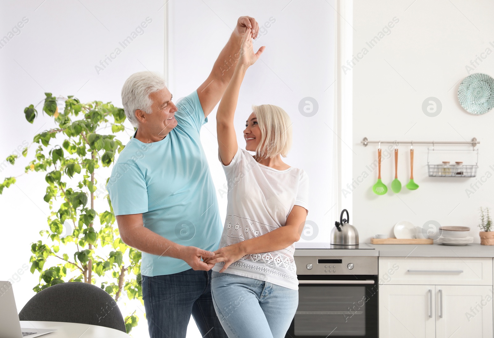 Photo of Happy mature couple dancing together in kitchen
