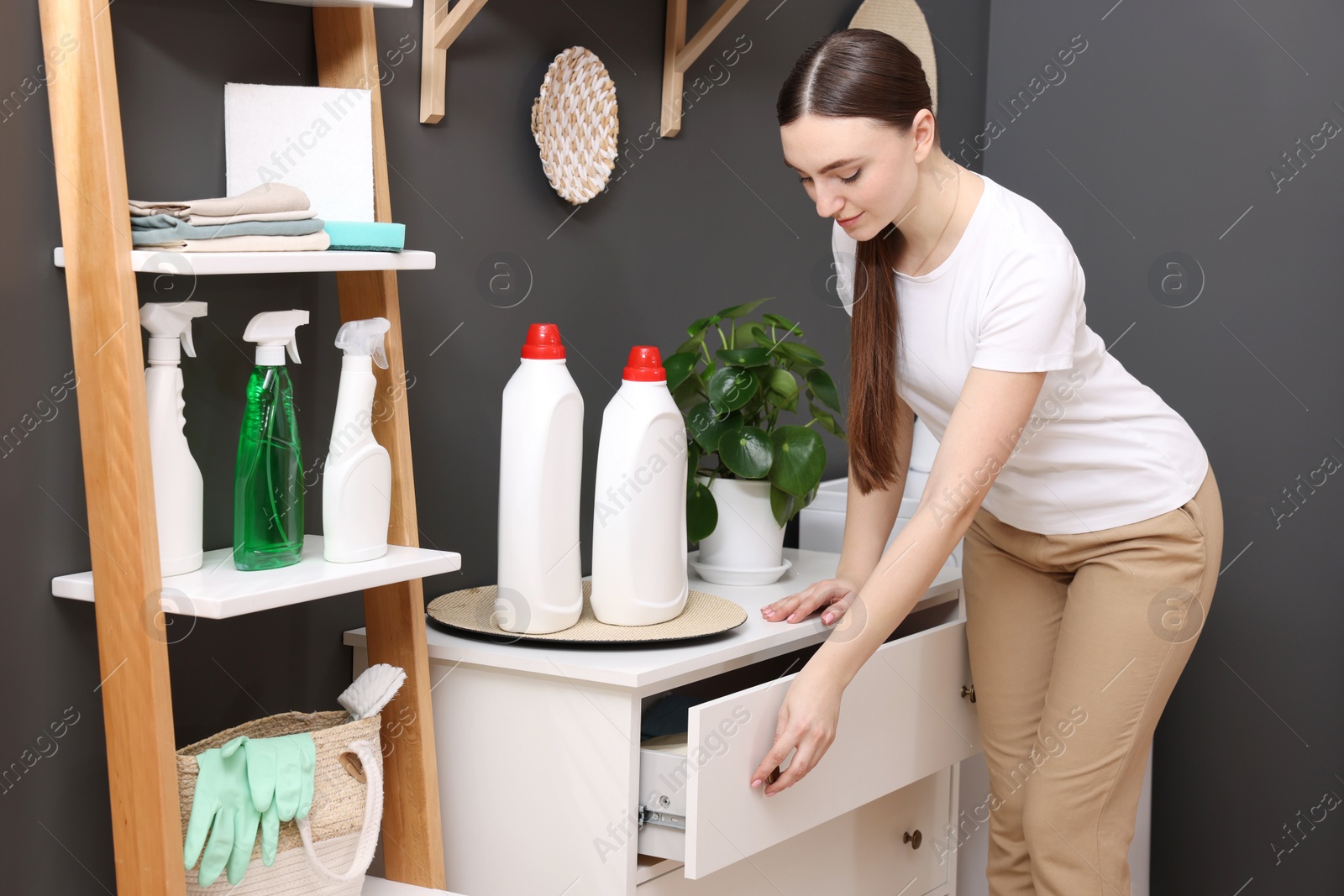 Photo of Beautiful woman opening drawer in laundry room