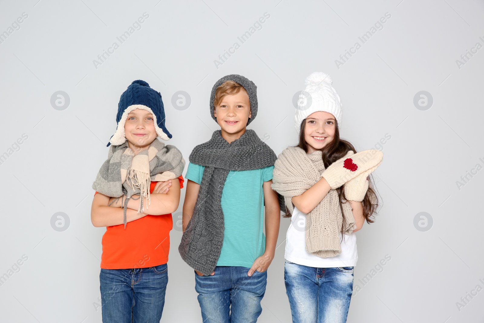 Photo of Cute little children in warm clothes posing on light background. Christmas celebration