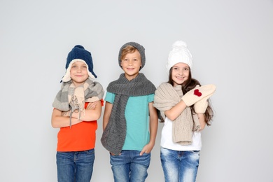 Photo of Cute little children in warm clothes posing on light background. Christmas celebration