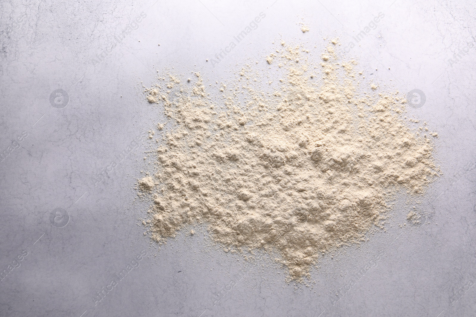 Photo of Pile of flour on light textured table, top view. Space for text