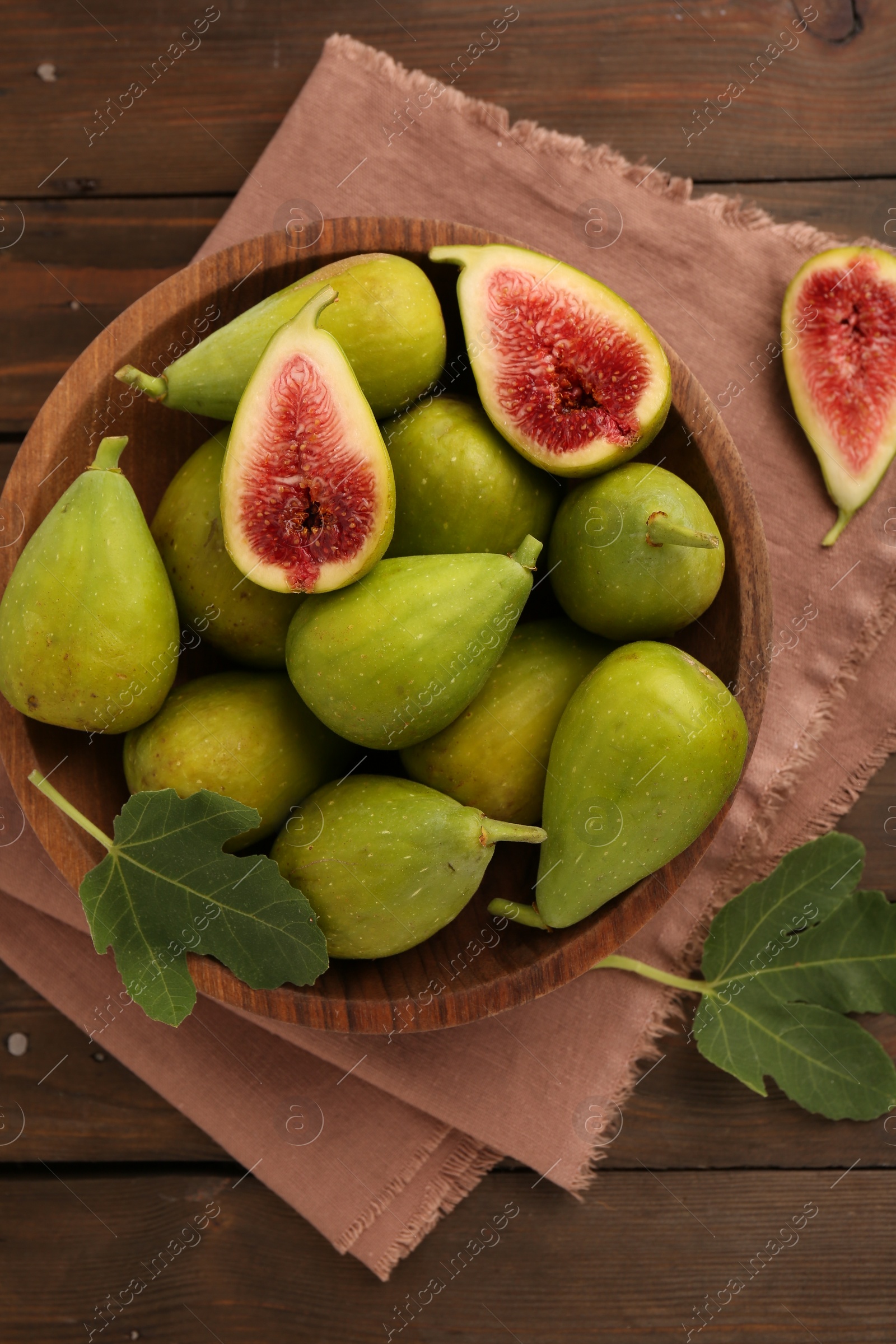 Photo of Cut and whole green figs on wooden table, flat lay