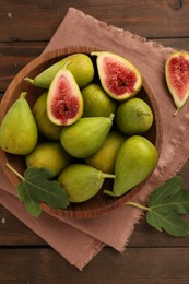 Cut and whole green figs on wooden table, flat lay