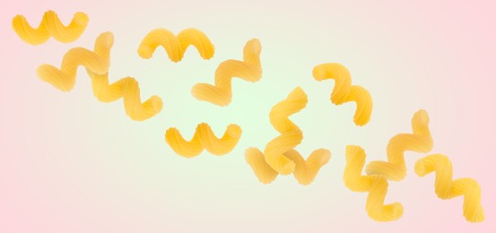 Raw cavatappi pasta falling on color background