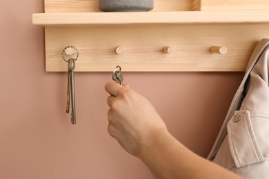 Photo of Woman taking keys from hanger in hallway, closeup