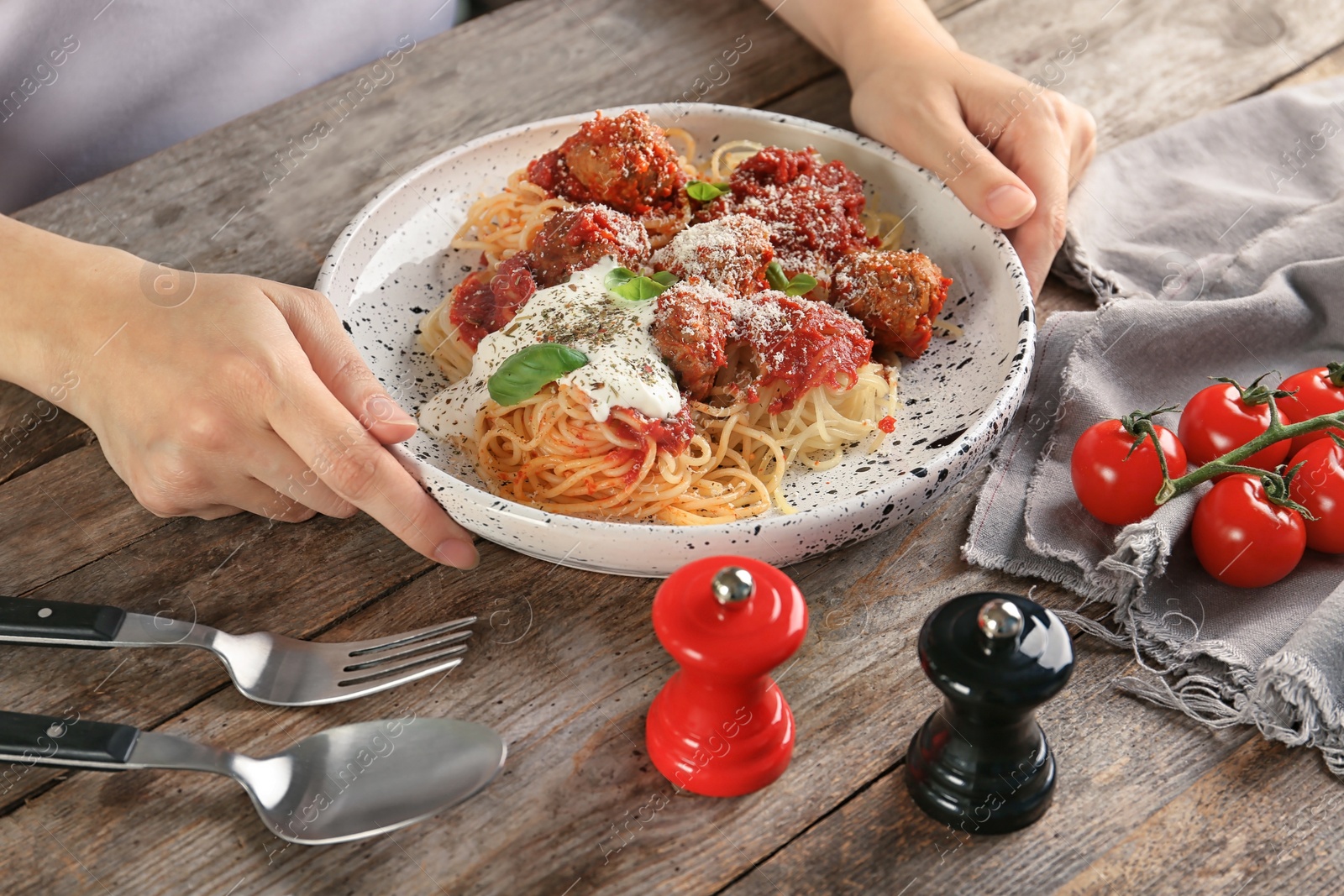 Photo of Woman having pasta with meatballs and tomato sauce at table, closeup