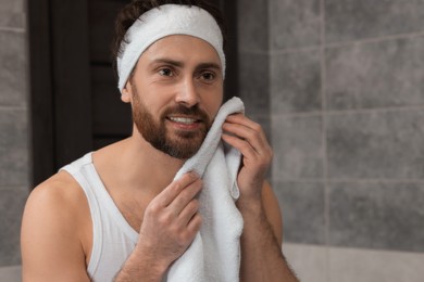 Washing face. Man with headband and towel in bathroom, space for text