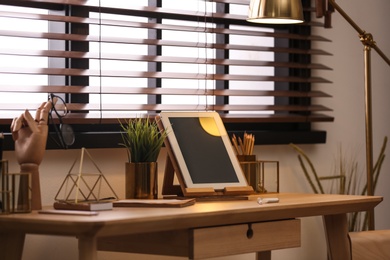 Stylish workplace with modern tablet on table at window. Ideas for interior design
